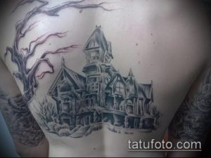 Фотография татуировки на лопатке, изображающей старый, заброшенный дом с голыми деревьями на фоне. Мрачный рисунок татуировки в стиле хоррор.