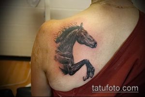 Фотография татуировки головы лошади, выполненной в стиле графики с использованием точечной техники и теней на плече.