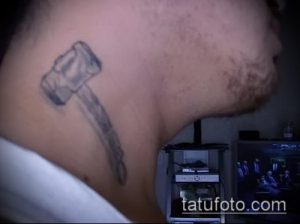 Фото тату молота Тора на шее, выполненного в черно-серых тонах. Простой и лаконичный рисунок татуировки.