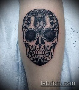Фото татуировки сахарного черепа на ноге, выполненной в стиле dotwork, с детальной проработкой узоров и орнаментов.
