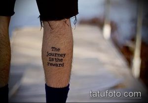Фото татуировки на икре: простая надпись "The journey is the reward" черным цветом. Минималистичный дизайн и лаконичный шрифт.