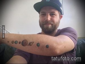 Мужчина с татуировкой планет Солнечной системы на предплечье. Изображены Меркурий, Венера, Земля, Марс, Юпитер, Сатурн и другие планеты.