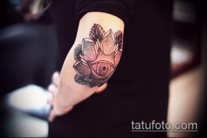 Фото тату глаз в цветке лотоса на локте. Графичный стиль, черные линии, точечная техника. Идеи для тату в стиле боди-арт.
