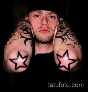 Фото тату: татуировка в стиле blackwork с изображением звезд на локтях мужчины. Черно-белый рисунок, четкие контуры, минималистичный стиль.