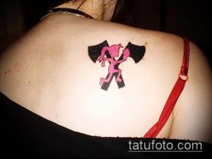 Фото татуировки с изображением персонажа Violent J из Insane Clown Posse на спине, выполненной в розовом цвете с черными контурами.