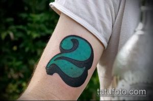 Цветная татуировка цифры '2' на руке. Стиль wave, плавные линии, зеленые и черные оттенки. Динамичный и оригинальный дизайн.