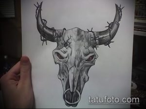 Черно-белый эскиз татуировки черепа быка, обвитого колючей проволокой. Рисунок выполнен карандашом на бумаге.