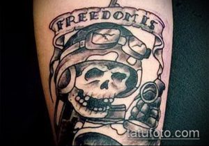 Фото тату на предплечье: череп в военной каске с надписью 'Freedom is'. Черно-белый рисунок в стиле олдскул.