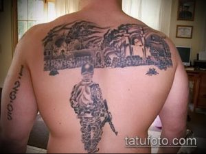 Фото тату на спине с изображением военной сцены, включающей солдат, здания и пейзаж. Детализированный и масштабный рисунок татуировки.