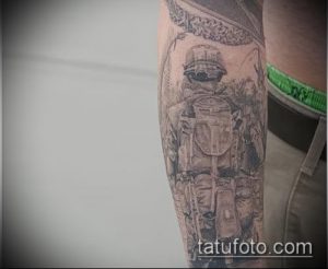 Фото тату солдата в военной форме с рюкзаком и оружием на руке. Рисунок выполнен в черно-белых тонах с использованием множества деталей.