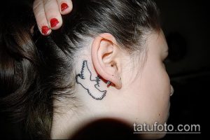 Фото тату маленького белого голубя за ухом. Простой и элегантный рисунок татуировки в стиле минимализм.