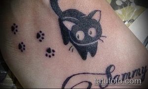 Фото тату: черная татуировка кошки с большими глазами и подписью 'Sammy' на коже. Милый и персонализированный рисунок.