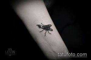 Фото минималистичной татуировки мухи на предплечье. Черно-белый рисунок с тонкими линиями и лаконичным дизайном.