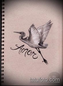 Фото тату аиста в полете с надписью "Amor" (любовь) под ним. Изображение выполнено в реалистичном стиле с использованием теней и полутонов.