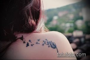 Фото тату одуванчика с летящими птицами на плече девушки. Черно-белый рисунок татуировки, выполненный в минималистичном стиле.