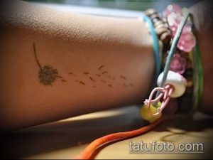Фото тату одуванчика, выполненного в коричневых тонах на женской руке. Маленький, изящный рисунок татуировки, идея для минималистичного дизайна.