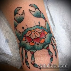 Фото традиционной татуировки краба на руке. Рисунок выполнен в ярких цветах с использованием классических элементов татуировки, таких как контуры и тени.