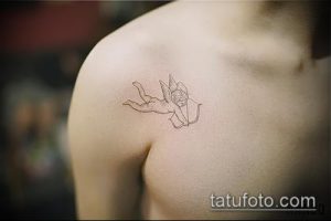 Фото минималистичной татуировки амура на плече. Изображение ангела с луком и стрелой, выполненное в черном цвете, в тонких линиях.