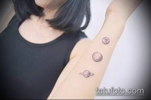 Фото тату трех планет на руке. Небольшие контурные рисунки Сатурна, Земли и другой планеты, выполненные в черном цвете. Минималистичный и стильный дизайн.