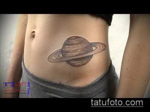 Фото классической татуировки Сатурна на женском животе. Рисунок выполнен в коричневых тонах с использованием линий и штриховки. Традиционный и элегантный дизайн.