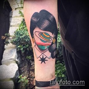 Фото тату: татуировка в стиле олдскул на руке, изображающая девушку с планетой Сатурн вместо головы. Яркие цвета и четкие контуры.