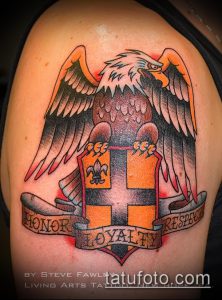 Фото тату на плече: орел, держащий щит с крестом и девизом 'Honor Loyalty Respect'. Яркий рисунок в стиле old school.