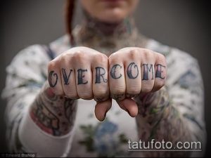 Фото тату: надпись 'OVERCOME' на фалангах пальцев рук. Мотивационная татуировка в стиле lettering.