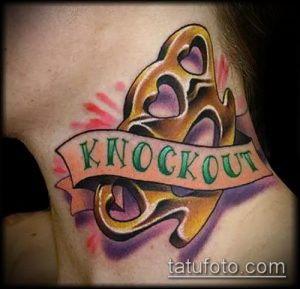 Фото тату: красочный рисунок кастета с надписью 'KNOCKOUT' на плече. Изображение выполнено в стиле олдскул с использованием ярких цветов и четких линий.