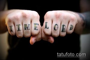Фото тату надписи 'TIME LORD' на костяшках пальцев. Черно-белый рисунок татуировки с футуристическим дизайном.