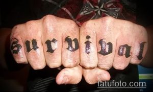 Фото тату на костяшках пальцев: надпись 'Survival' выполнена черными чернилами в готическом стиле, создавая эффектный и дерзкий образ.