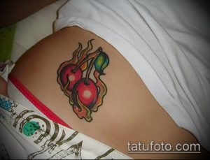 Фото татуировки с изображением двух вишен, объятых пламенем, на нижней части спины.