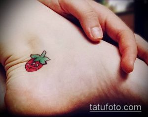 Фото миниатюрной татуировки клубники на лодыжке. Небольшой, аккуратный рисунок татуировки с яркими цветами.