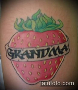 Фото тату клубники с надписью 'Grandma' на руке. Яркий рисунок татуировки в стиле олдскул с четкими контурами и насыщенным красным цветом.