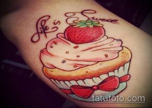 Фото тату клубники на кексе с надписью 'Life is sweet'. Яркий и милый рисунок татуировки в стиле олдскул.