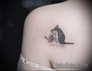 Фото тату на плече: две кошки, одна серая, другая черная, обнимаются. Нежный и милый рисунок татуировки, выполненный в реалистичном стиле.