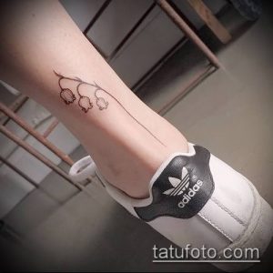 Минималистичное фото тату ландышей на женской лодыжке. Тонкие линии, нежные цветы, изящный дизайн. Идеально для любителей ботанических татуировок.