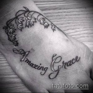 Фото тату: рисунок ландышей и надписи "Amazing Grace" на запястье, выполненный в черном цвете. Эскиз тату выглядит нежно и символично.