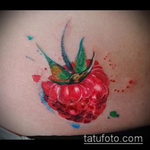 Фото акварельной татуировки малины на коже. Нежные розовые и красные оттенки, размытые края и брызги краски создают эффект акварельного рисунка.