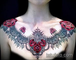 Фото тату с розами и кружевным узором на груди. Красные и черные цвета, детальная проработка лепестков и орнамента.