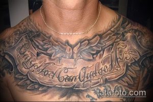 Фото тату с изображением ангельских крыльев и надписью "God Can Judge Me" на груди мужчины. Черно-серый рисунок в стиле реализм.