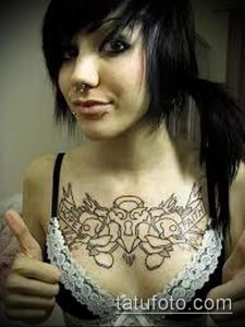 Фото тату на груди с изображением черепа, украшенного розами и лентами, выполненного в черно-белой графике.