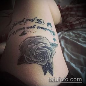 Фото тату: реалистичная роза с каплями росы и надписью "Sometimes to find yourself you need to lose yourself" на бедре.