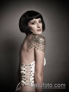 Фото тату на плече девушки: стилизованный узор, напоминающий кружево или плетение, выполненный в черно-белой гамме. Детализированный рисунок татуировки.