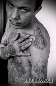 Фото тату тюремных надписей и рисунков на теле мужчины, демонстрирующее сложный узор и символику заключенных.