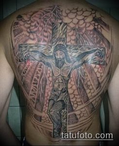 Фото тату распятия на спине. Черно-серый рисунок татуировки с изображением Иисуса Христа на кресте и детальным фоном.