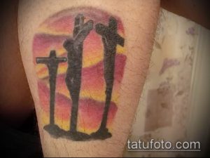 Фото тату трех распятий на фоне заката, выполненного в ярких и насыщенных цветах на ноге.