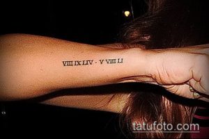 Фото тату: черные римские цифры 'VIII.XLIV.V.VIII' на запястье, выполненные тонкой линией. Идеально для тех, кто предпочитает лаконичность.