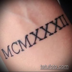 Фото тату: черные римские цифры 'MCMXXI' на запястье, выполненные в простом и лаконичном стиле. Идеально для тех, кто предпочитает минимализм.