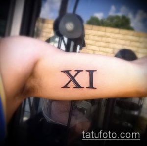 Фото тату: Минималистичная татуировка с римской цифрой 'XI' на руке. Черный цвет, четкие линии.