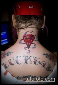 Фото татуировки бриллианта с надписью 'Lucky' на шее. Яркий и привлекающий внимание рисунок татуировки.